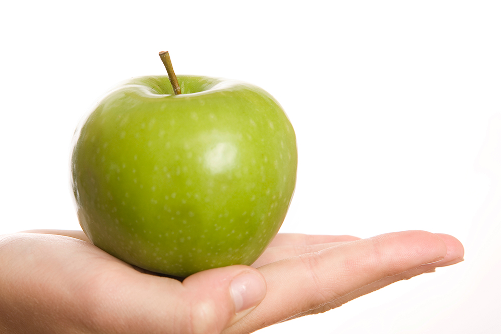 Ein grüner Apfel auf einer ausgestreckten Hand